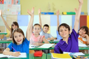 Elementary-school-students-raising-hands-in-classroom.