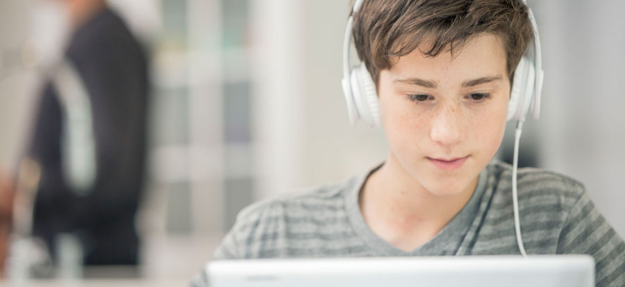 student on a computer listening to an audiobook with headphones