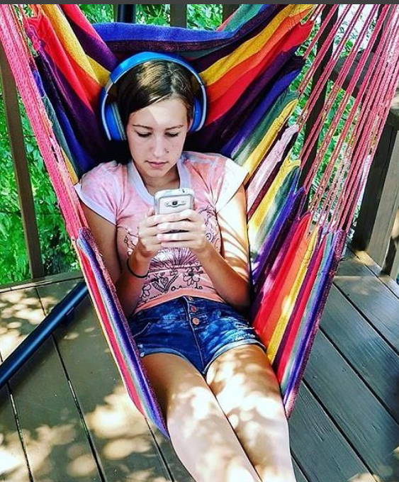 girl reading with headphones and a smartphone in a hammock. 