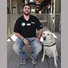 Bryan Duarte sitting on bench with service dog beside him