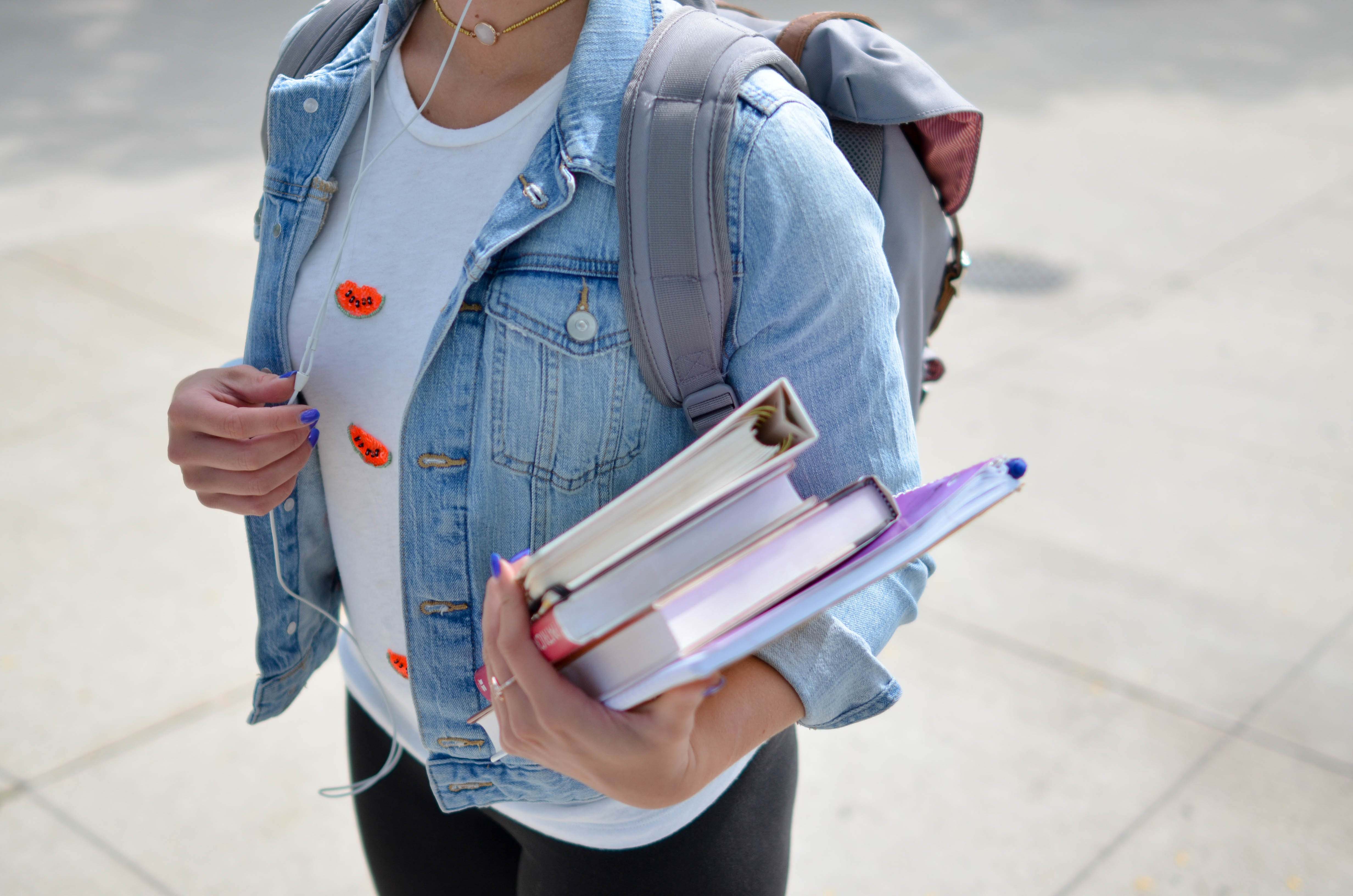 Torso of girl student holding books and a backpack