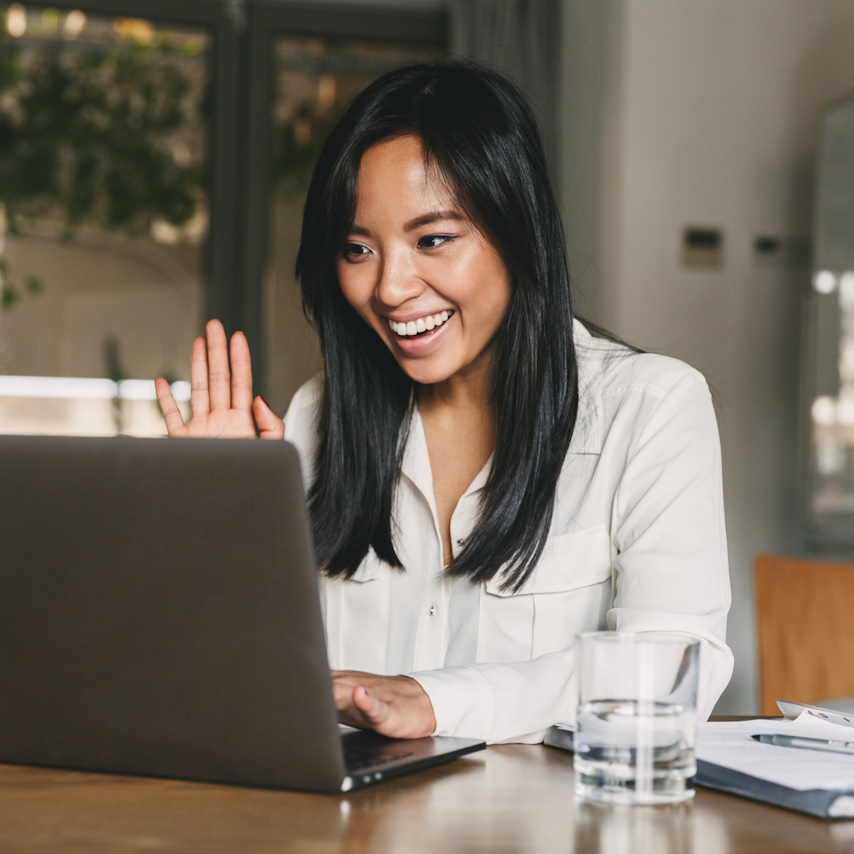 Woman on computer smiling and waving