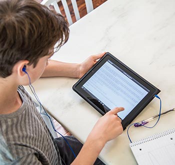 Student reading an audiobook on his tablet