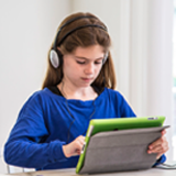 photo of young female student enjoying audiobooks on their tablet